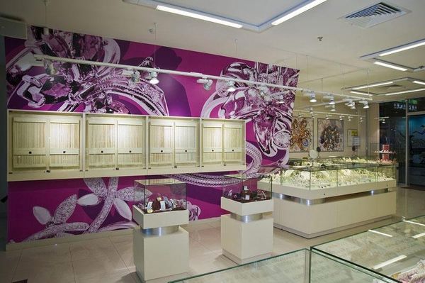 Modern jewelry salon with wall-mounted display cabinets, island vitrines and a long glass counter.