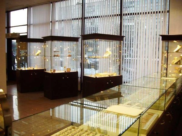 Dark wood island showcases and a glass jewelry counter beside a window wall.