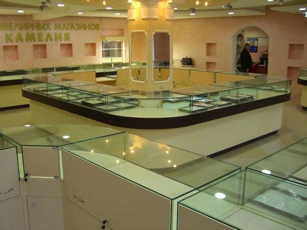 U-shaped jewelry sales island with a dark counter edge and surrounding glass display cases.
