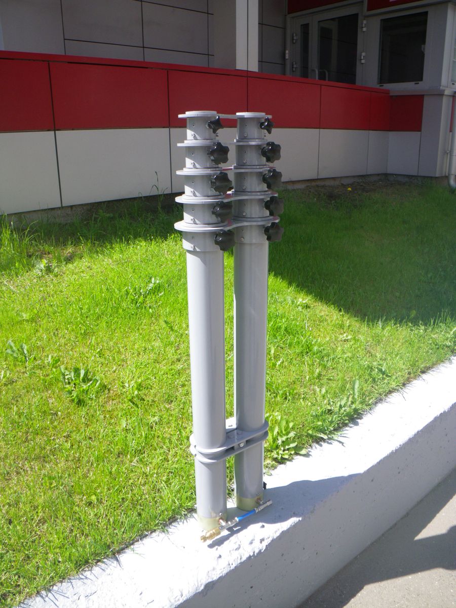 Paired white telescopic mast columns standing on a concrete curb.