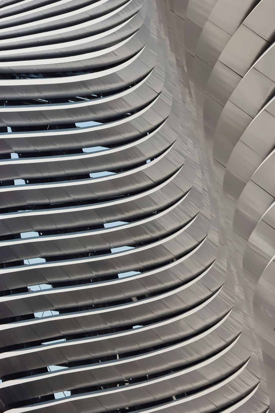 Curved metallic louver facade with vertical fins, photographed in daylight.