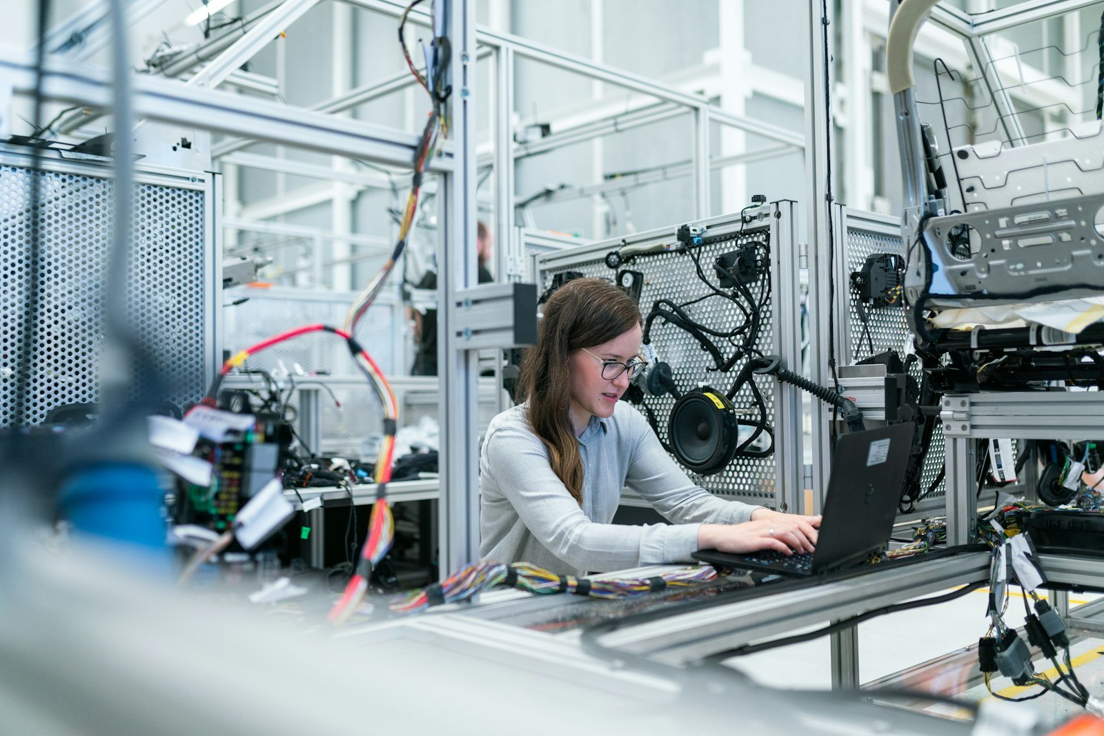 Engineer reviewing technical work on a laptop beside an industrial assembly station.